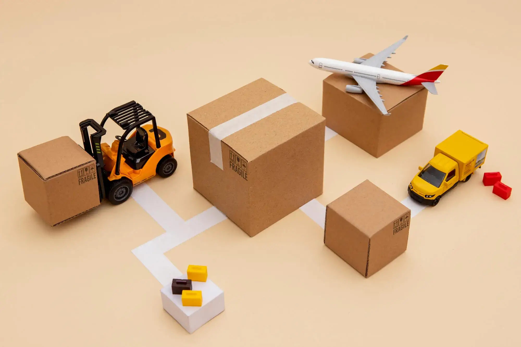 Miniature forklift, airplane, and delivery truck transporting cardboard boxes along a connected white path, illustrating the concept of what is logistic service.