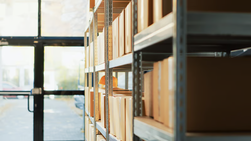 Boxes on metal shelves in a warehousing and fulfillment storage.